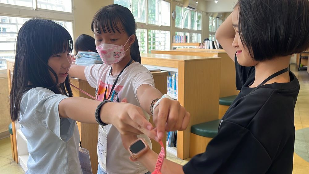 Children measuring the length of an arm with a tape measure in the school library