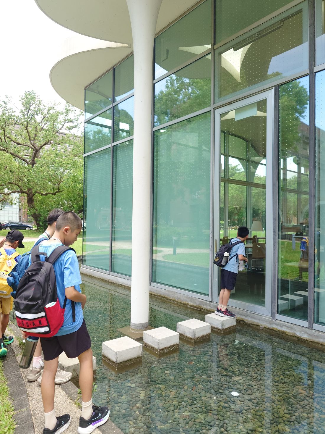 Children looking up at and observing the NTU College of Social Sciences library