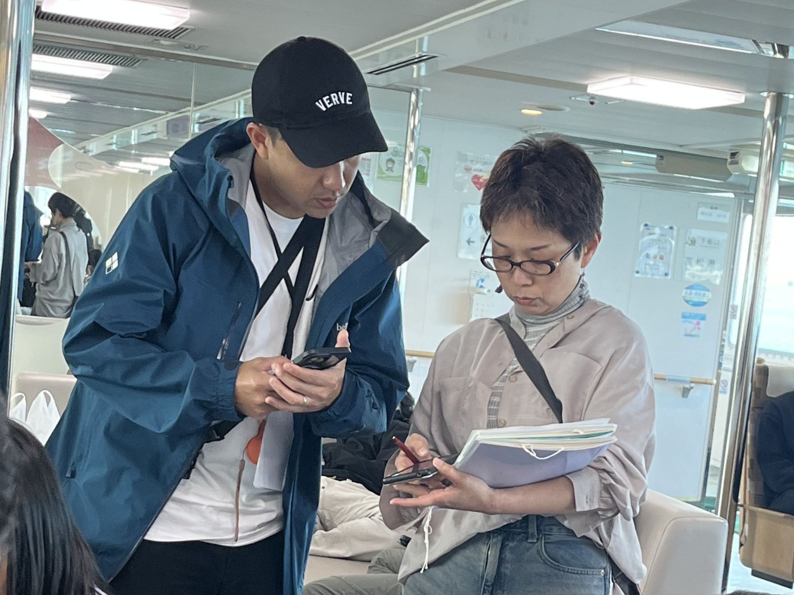 高松港へのフェリーで、翻訳機を手に語り合うJason先生と野上